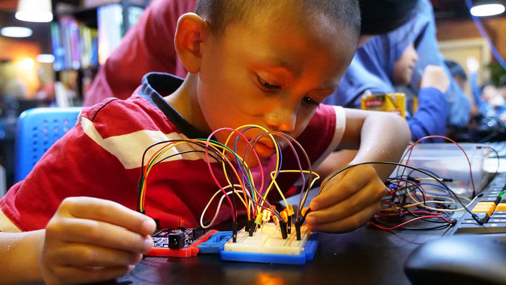 Kidocode student wiring a real build, math becoming the tool that makes it work