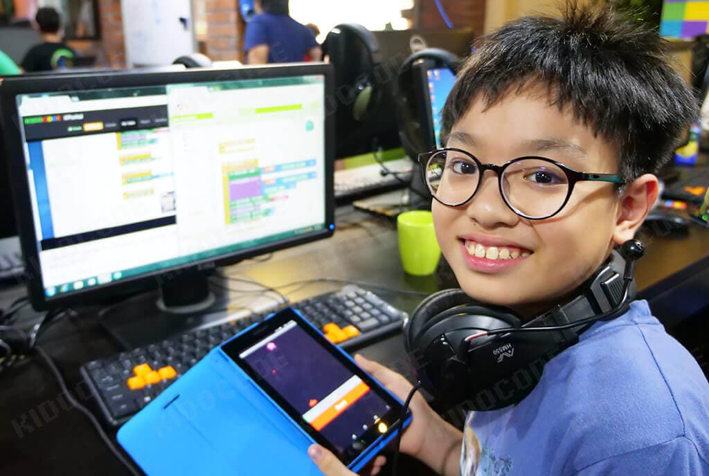 Kidocode student building a game on tablet, math working invisibly behind it