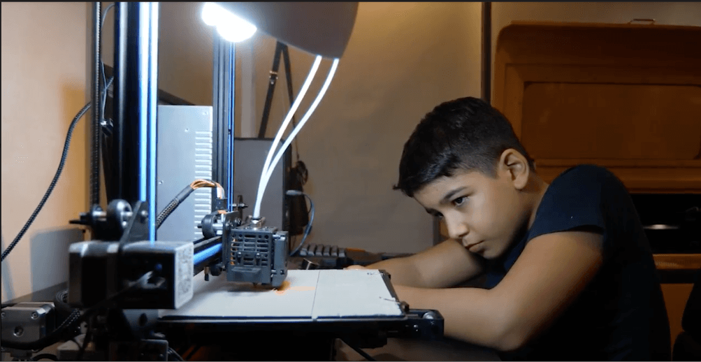Boy watching a 3D printer build his design